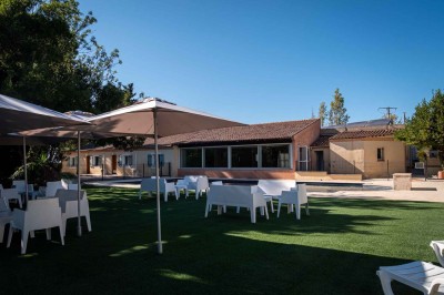 Vue aérienne d'une maison avec toit en tuiles, piscine rectangulaire et jardin arboré dans un cadre rural.