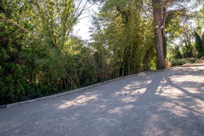 Vue aérienne d'une maison avec toit en tuiles, piscine rectangulaire et jardin arboré dans un cadre rural.