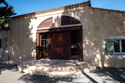 Vue aérienne d'une maison avec toit en tuiles, piscine rectangulaire et jardin arboré dans un cadre rural.