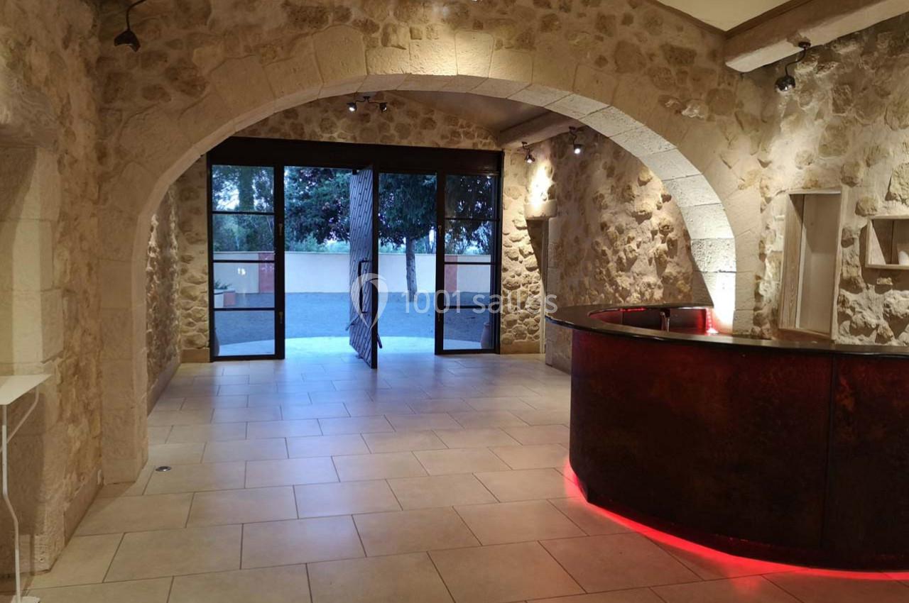 Salle en pierre avec un comptoir arrondi éclairé, donnant sur une porte vitrée ouverte vers l'extérieur.