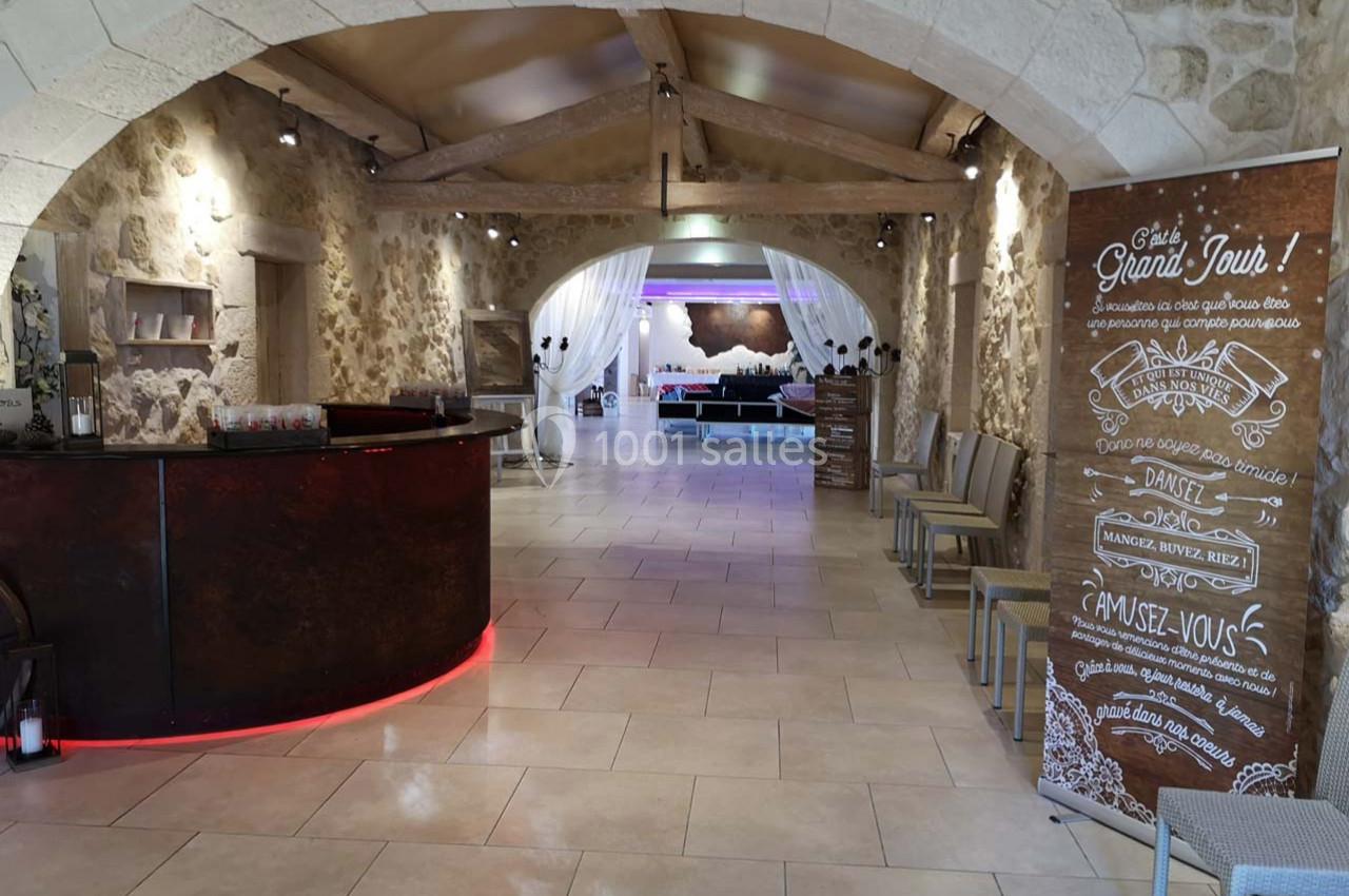 Accueil d'un espace événementiel avec comptoir en bois, affiches informatives et salle lumineuse en arrière-plan.