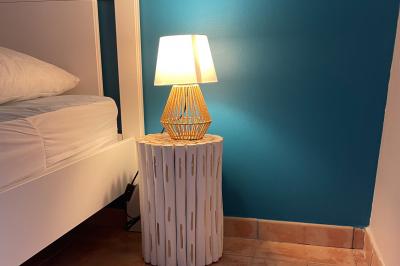 Chambre avec un lit double, mur décoré d'une photo de plage et éclairage doux avec appliques et lampes de chevet.