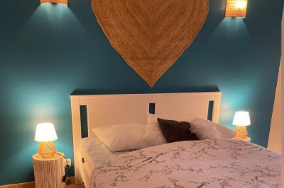 Chambre avec un lit double, mur décoré d'une photo de plage et éclairage doux avec appliques et lampes de chevet.