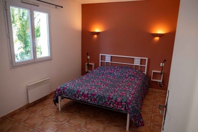 Chambre avec un lit double, mur décoré d'une photo de plage et éclairage doux avec appliques et lampes de chevet.