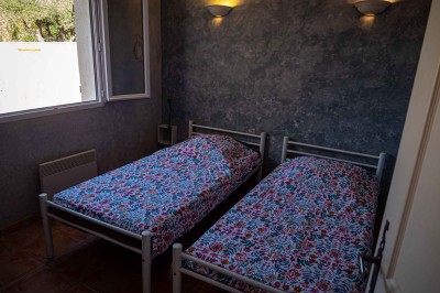 Chambre avec un lit double, mur décoré d'une photo de plage et éclairage doux avec appliques et lampes de chevet.