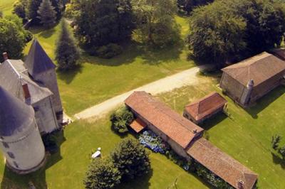 Vue d'un château en pierre entouré d'arbres et d'une pelouse bien entretenue sous un ciel dégagé.
