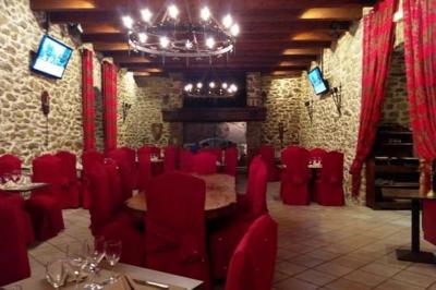 Terrasse en gravier avec parasols rouges, bordée d'un muret en pierre, offrant une vue sur des montagnes verdoyantes.