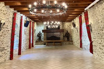 Terrasse en gravier avec parasols rouges, bordée d'un muret en pierre, offrant une vue sur des montagnes verdoyantes.