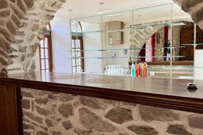 Terrasse en gravier avec parasols rouges, bordée d'un muret en pierre, offrant une vue sur des montagnes verdoyantes.