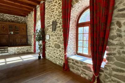 Terrasse en gravier avec parasols rouges, bordée d'un muret en pierre, offrant une vue sur des montagnes verdoyantes.