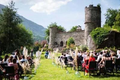 Terrasse en gravier avec parasols rouges, bordée d'un muret en pierre, offrant une vue sur des montagnes verdoyantes.
