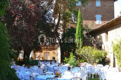 Vue sur les toits d'une ville avec un clocher en pierre et une tour en bois surmontée d'une cloche.