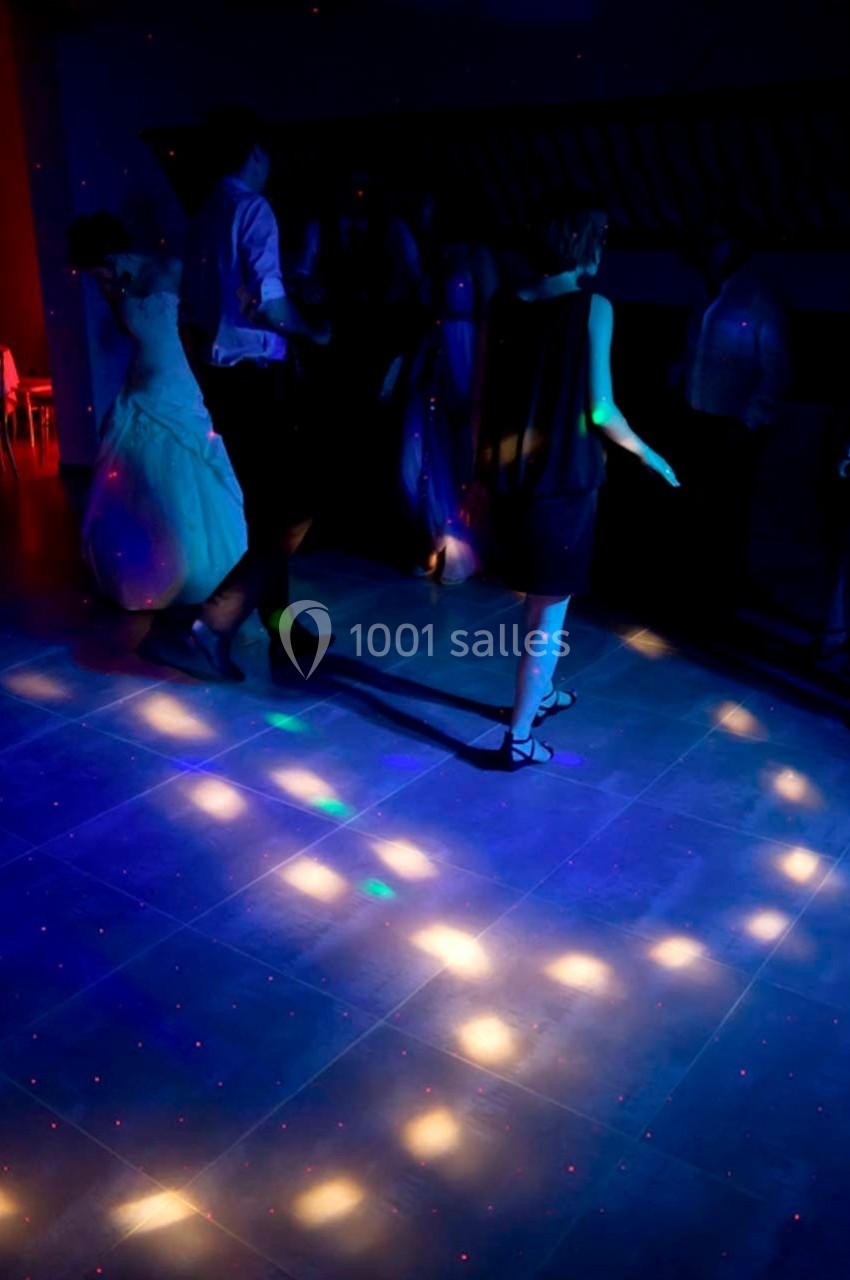 Personnes dansant sur une piste éclairée par des lumières colorées dans une ambiance sombre.