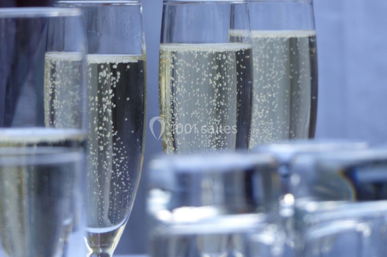 Quatre flûtes remplies de champagne pétillant sur une table, avec des verres flous en premier plan.