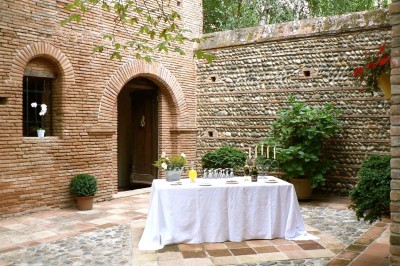 Entrée en briques rouges avec une porte verte ouverte et des lanternes suspendues à motifs zigzag.