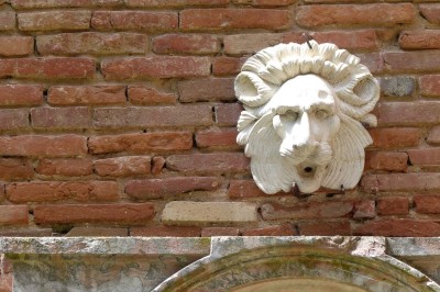 Entrée en briques rouges avec une porte verte ouverte et des lanternes suspendues à motifs zigzag.