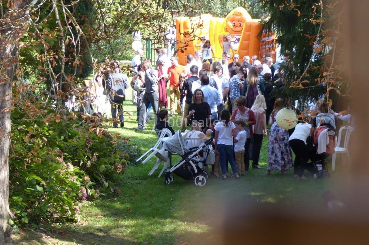 Groupe de personnes rassemblées dans un jardin avec des structures gonflables en arrière-plan.