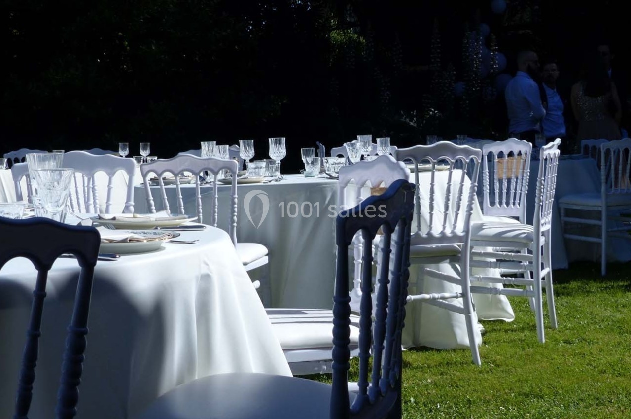 Tables et chaises blanches disposées sur une pelouse, préparées pour un événement en extérieur.
