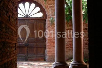 Vue sur les toits d'une ville avec un clocher en pierre et une tour en bois surmontée d'une cloche.