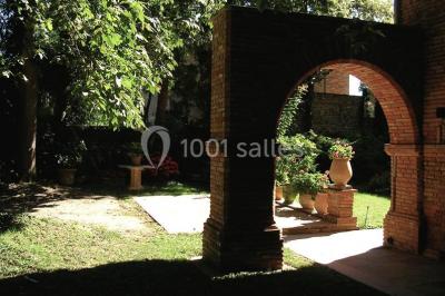 Vue sur les toits d'une ville avec un clocher en pierre et une tour en bois surmontée d'une cloche.