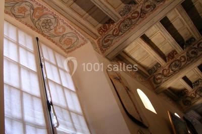 Vue sur les toits d'une ville avec un clocher en pierre et une tour en bois surmontée d'une cloche.