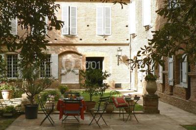 Vue sur les toits d'une ville avec un clocher en pierre et une tour en bois surmontée d'une cloche.