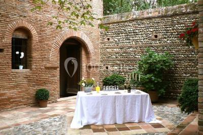 Vue sur les toits d'une ville avec un clocher en pierre et une tour en bois surmontée d'une cloche.