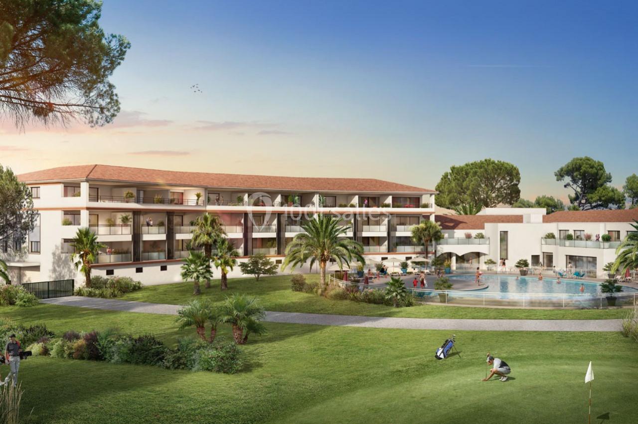 Vue d'un complexe résidentiel avec piscine, espaces verts et architecture méditerranéenne sous un ciel dégagé.