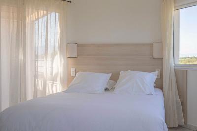 Vue d'un complexe résidentiel avec piscine, espaces verts et architecture méditerranéenne sous un ciel dégagé.