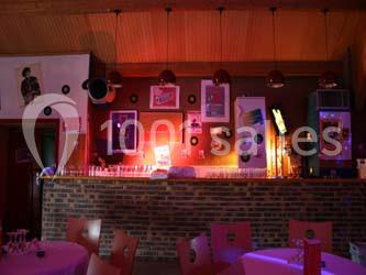 Bar rétro avec mur de briques, affiches vintage, vinyles accrochés et éclairage tamisé dans une ambiance chaleureuse.