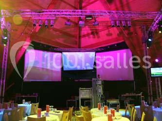 Salle de réception avec tables dressées, éclairage coloré et écrans géants projetant des images.