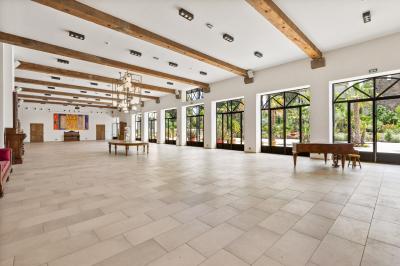 Chambre lumineuse avec lit double, tête de lit rouge, murs en pierre, grandes fenêtres et mobilier classique.