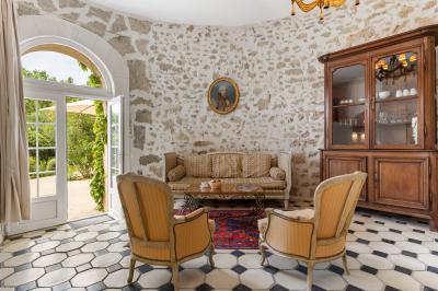 Chambre lumineuse avec lit double, tête de lit rouge, murs en pierre, grandes fenêtres et mobilier classique.