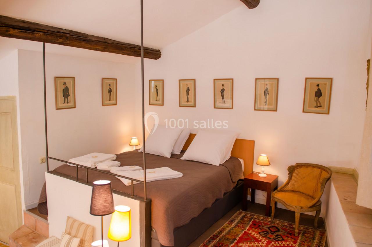 Chambre lumineuse avec lit double, linge de lit marron, décorations murales et mobilier en bois dans un style rustique.