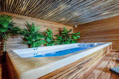 Chambre lumineuse avec lit double, tête de lit rouge, murs en pierre, grandes fenêtres et mobilier classique.