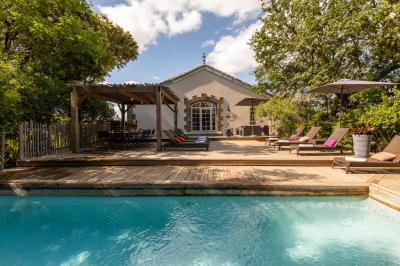 Chambre lumineuse avec lit double, tête de lit rouge, murs en pierre, grandes fenêtres et mobilier classique.