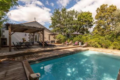 Chambre lumineuse avec lit double, tête de lit rouge, murs en pierre, grandes fenêtres et mobilier classique.