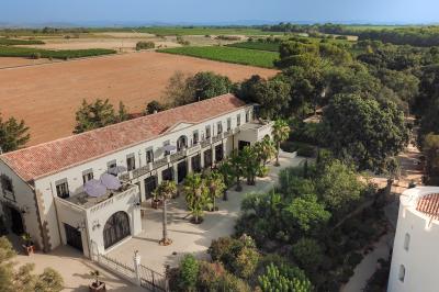Chambre lumineuse avec lit double, tête de lit rouge, murs en pierre, grandes fenêtres et mobilier classique.
