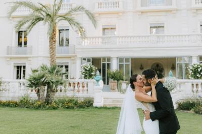 Chambre lumineuse avec lit double, tête de lit rouge, murs en pierre, grandes fenêtres et mobilier classique.