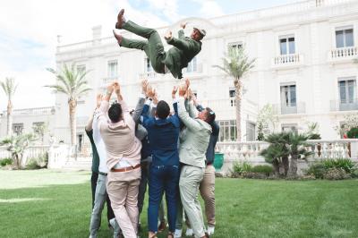 Chambre lumineuse avec lit double, tête de lit rouge, murs en pierre, grandes fenêtres et mobilier classique.