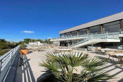 Bain à remous entouré de plantes et de transats sur une terrasse en bois avec vue dégagée.