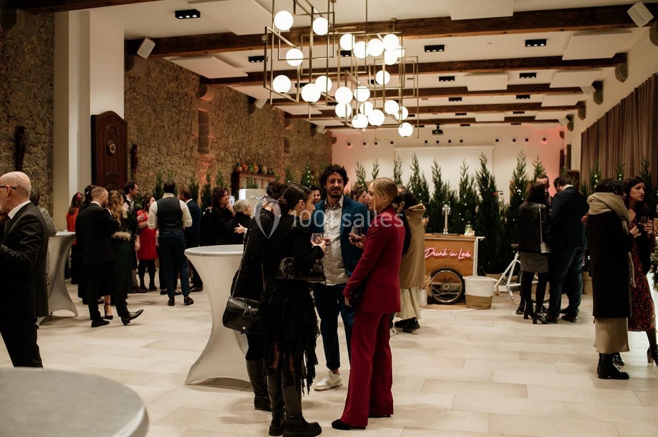 Personnes discutant dans une salle élégante avec des tables hautes, des luminaires modernes et une décoration festive.