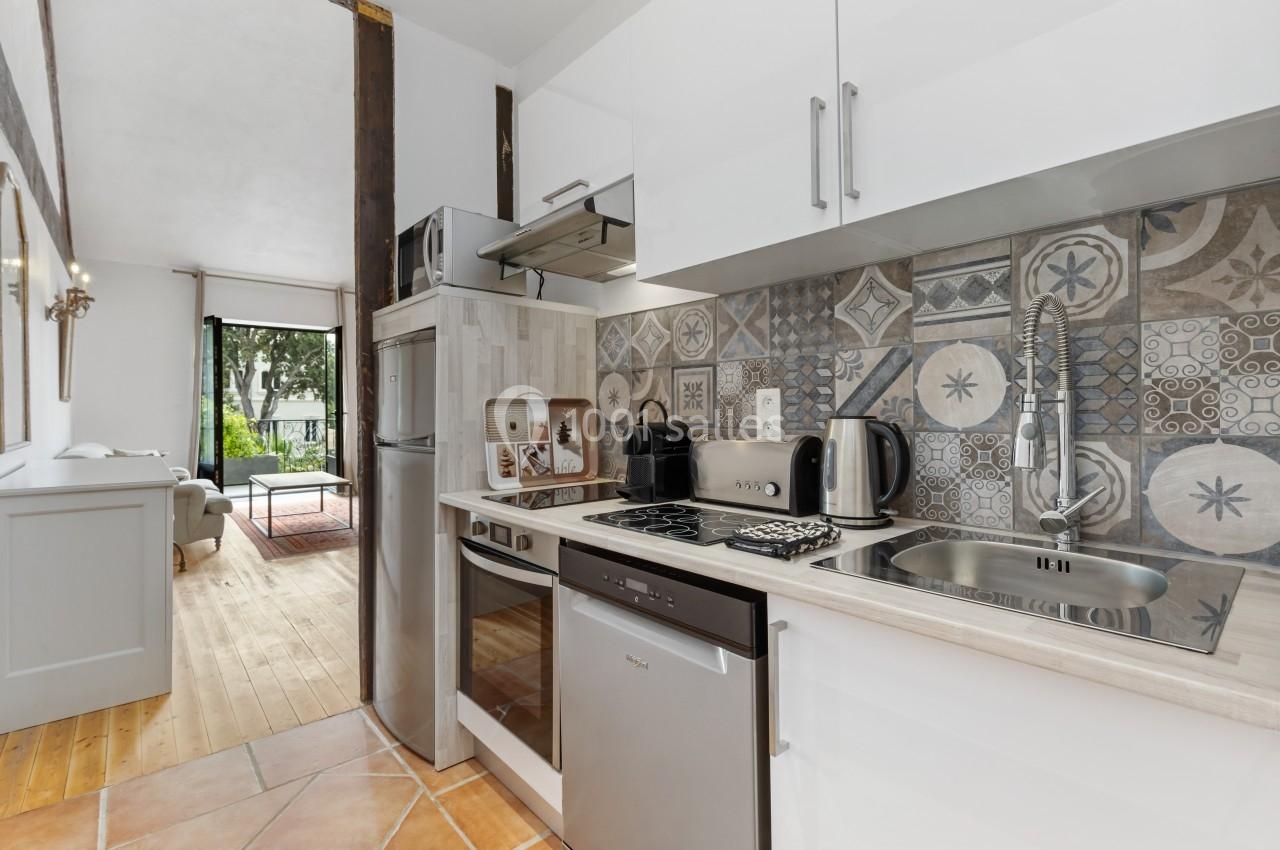 Cuisine moderne avec crédence en carreaux décoratifs, équipée d'électroménagers et ouverte sur un salon lumineux.