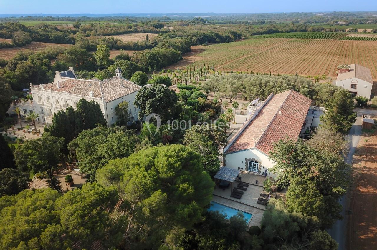 Vue aérienne d'un domaine avec bâtiments anciens entourés de jardins, vignobles et arbres, en pleine campagne.