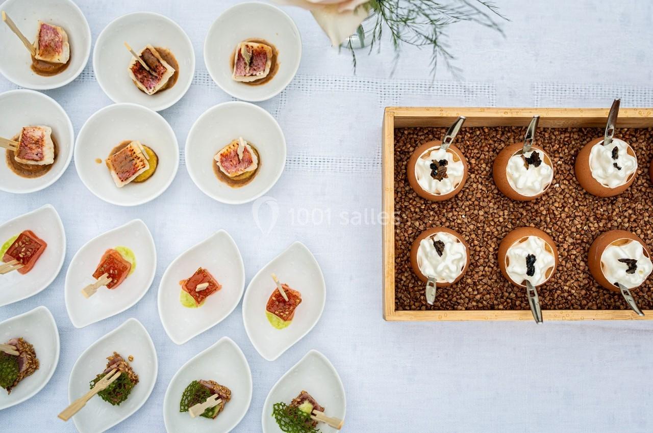 Assortiment de bouchées gastronomiques présentées dans des assiettes individuelles sur une table blanche.