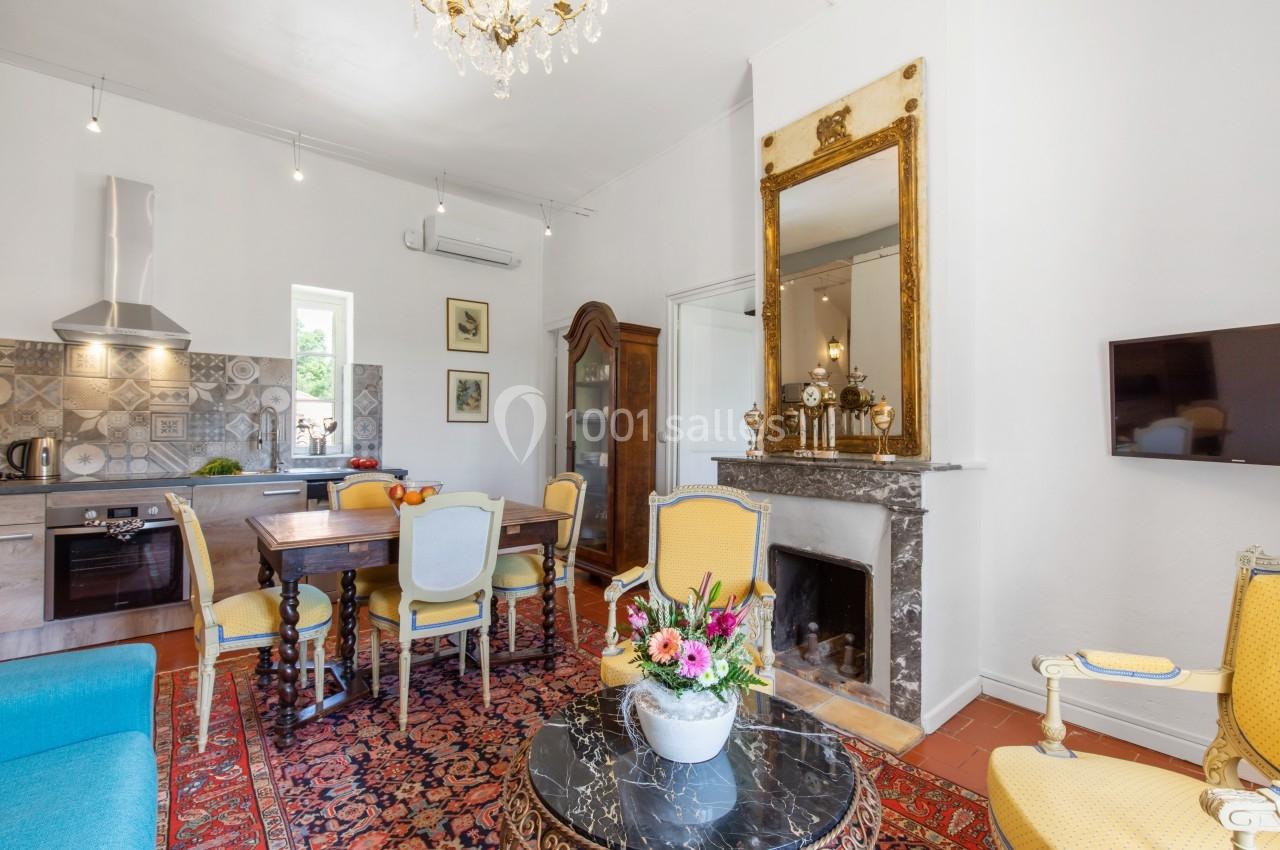 Salle de séjour lumineuse avec cheminée, table à manger, cuisine ouverte et décoration classique.