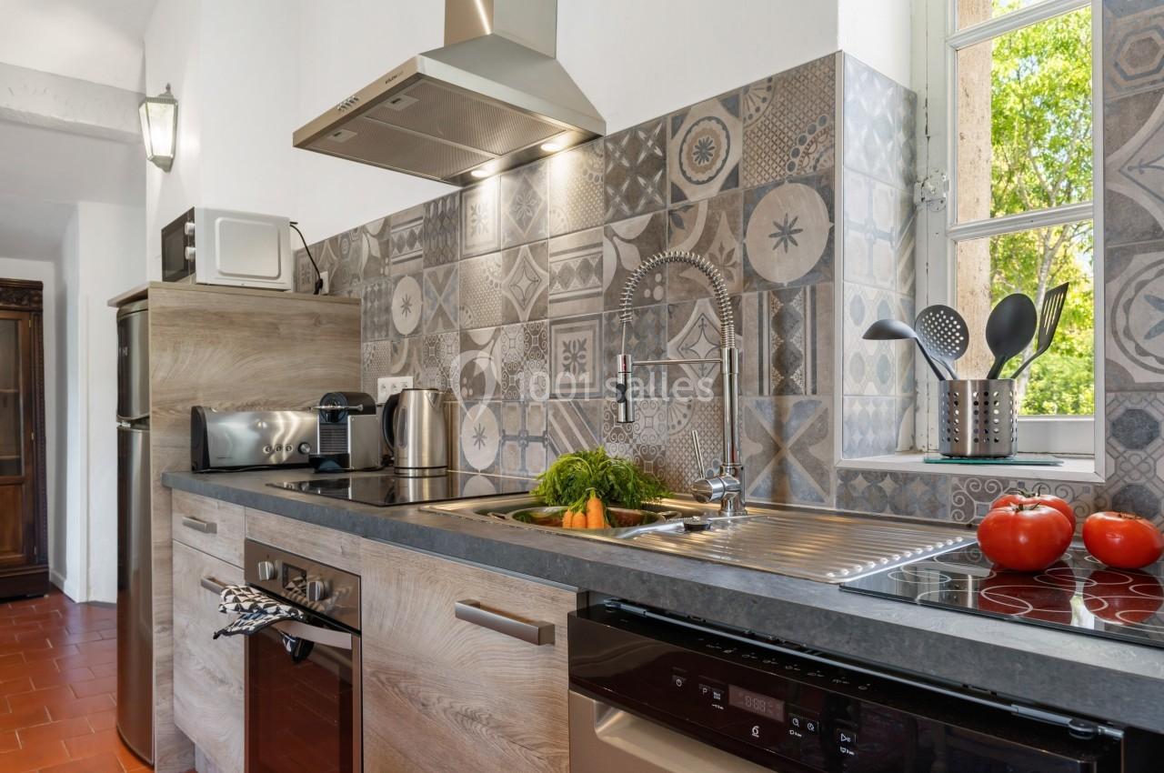 Cuisine moderne avec plan de travail en bois, crédence en carreaux décoratifs, évier, électroménagers et fenêtre donnant sur…