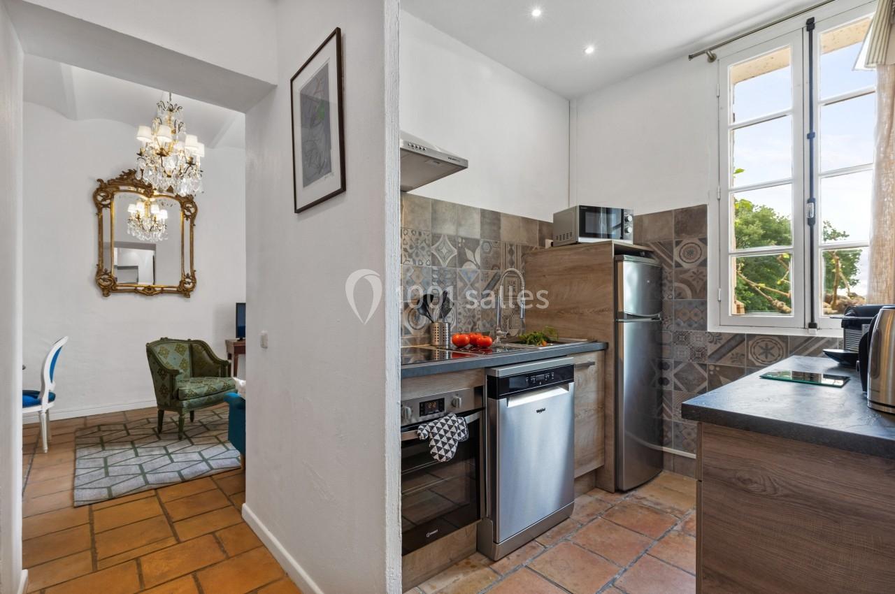 Cuisine lumineuse avec électroménagers modernes, carrelage décoratif, et vue sur un espace de vie et l'extérieur.