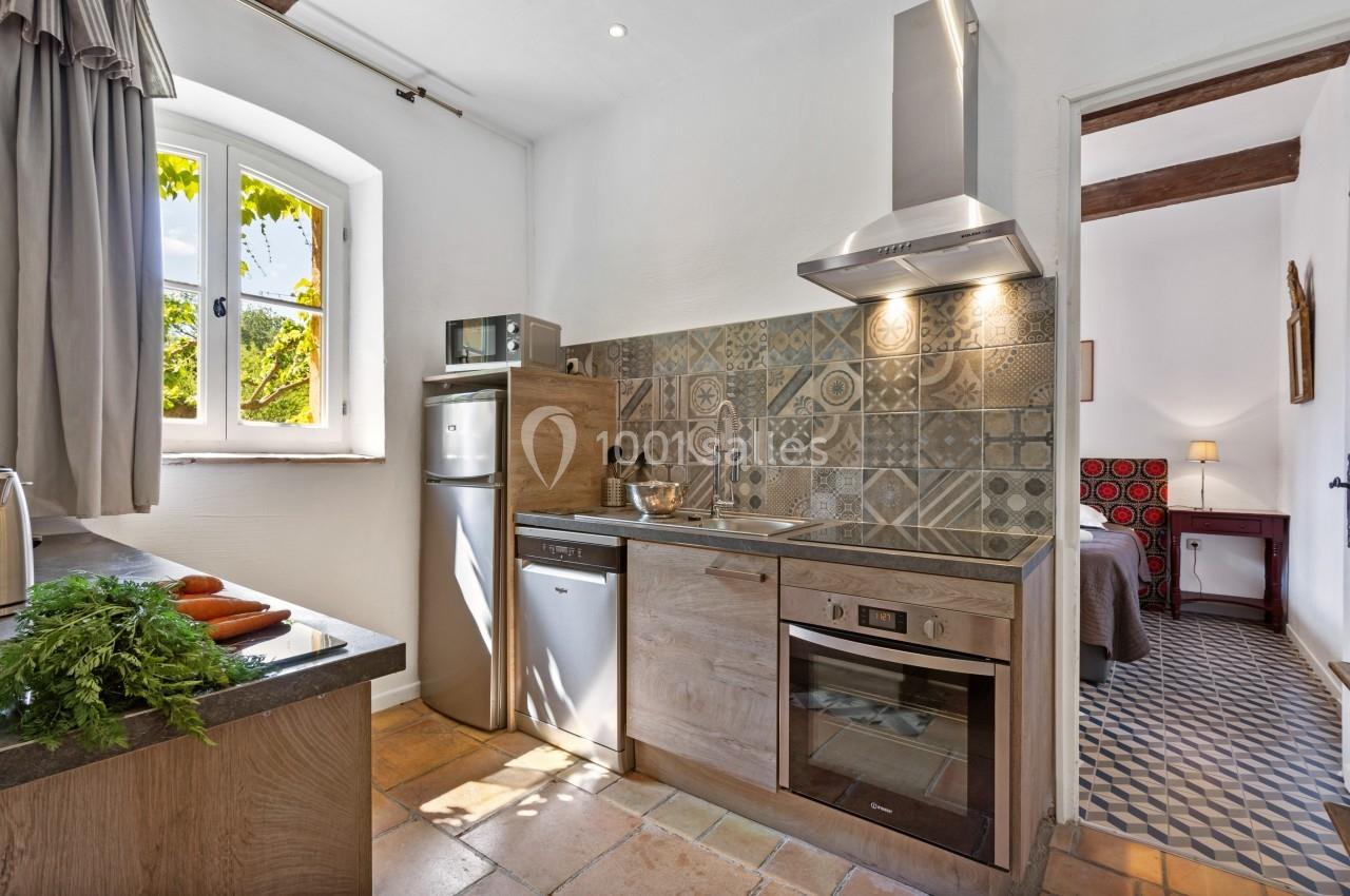 Cuisine lumineuse avec plan de travail en bois, carrelage décoratif, électroménagers modernes et vue sur un jardin.