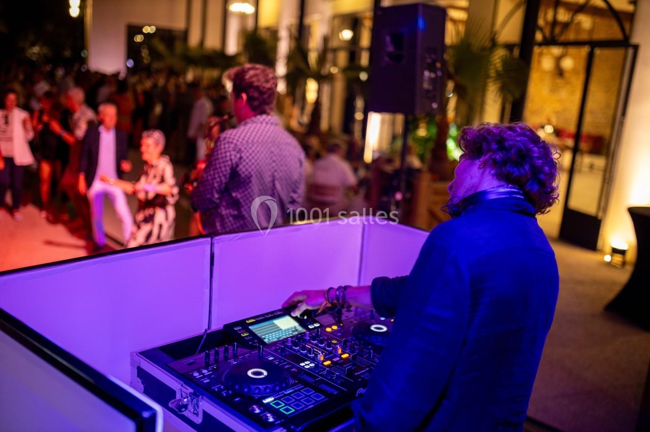 Un DJ mixe de la musique lors d'un événement en soirée avec des invités dansant en arrière-plan.